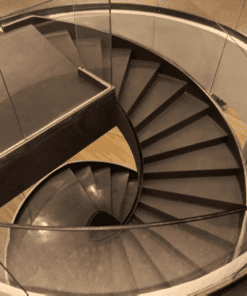 Escada helicoidal com guarda corpo de vidro curvo executada por Escadas Especiais em um ambiente hall de entrada principal de uma edifício residencial