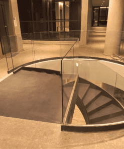 Escada helicoidal com guarda corpo de vidro curvo executada por Escadas Especiais em um ambiente hall de entrada principal de uma edifício residencial