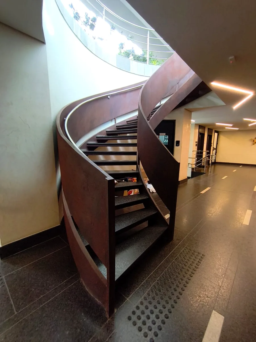 Detalhe de escada helicoidal metálica de alto padrão em aço corten com acabamento sob medida