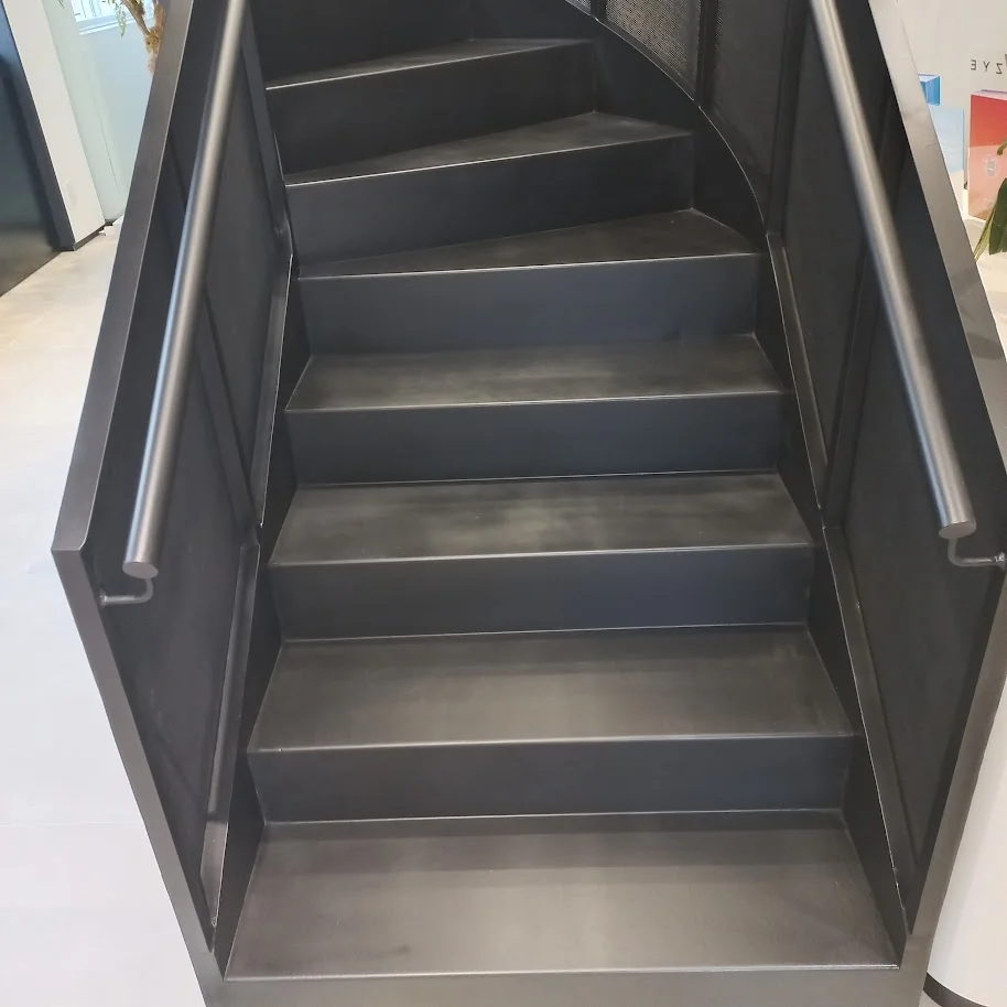 Detalhe dos degraus metálicos pretos de escada helicoidal em espaço corporativo de alto padrão em São Paulo