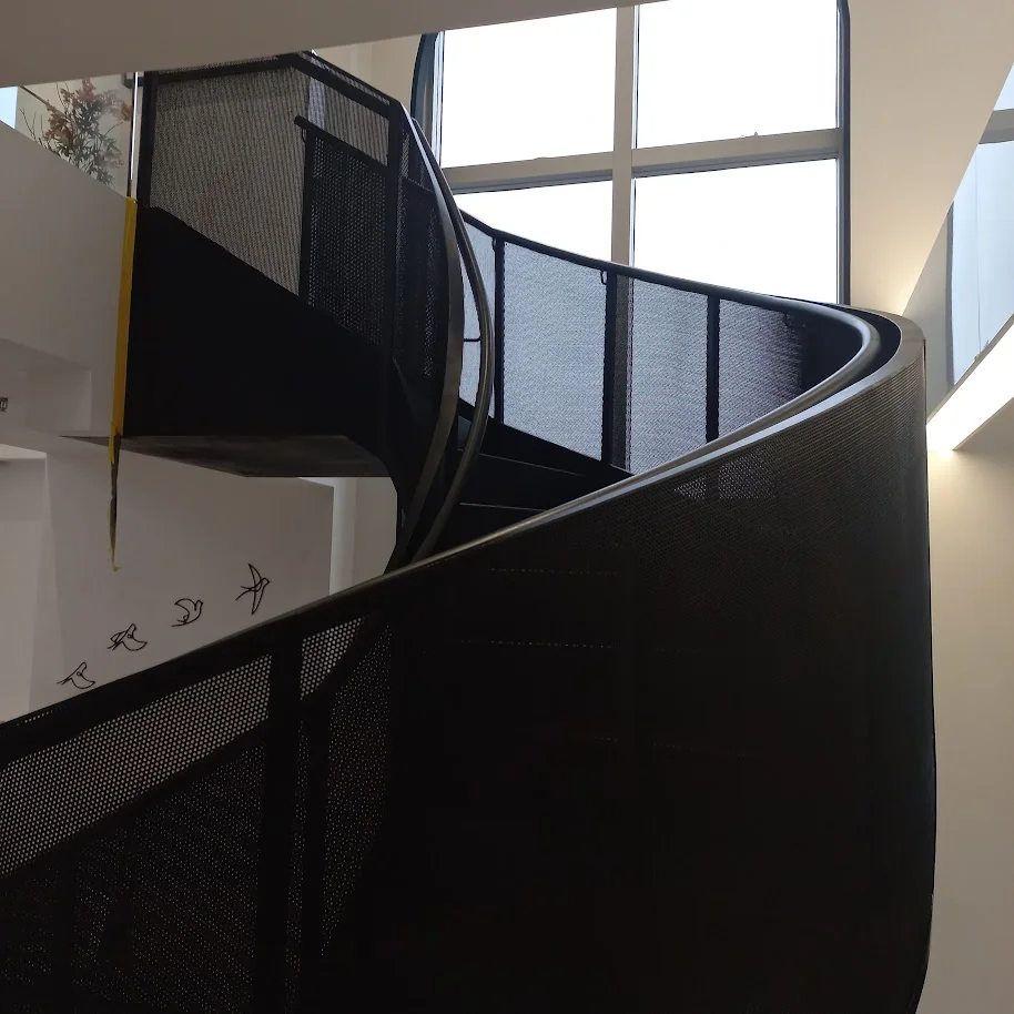 Vista dramática de baixo para cima de escada helicoidal metálica preta como escultura em espaço de saúde de alto padrão em São Paulo