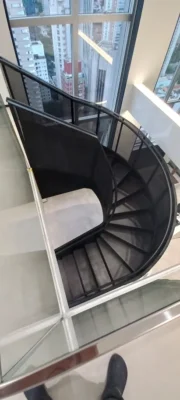Vista dramática de baixo para cima de escada helicoidal metálica preta como escultura em espaço de saúde de alto padrão em São Paulo