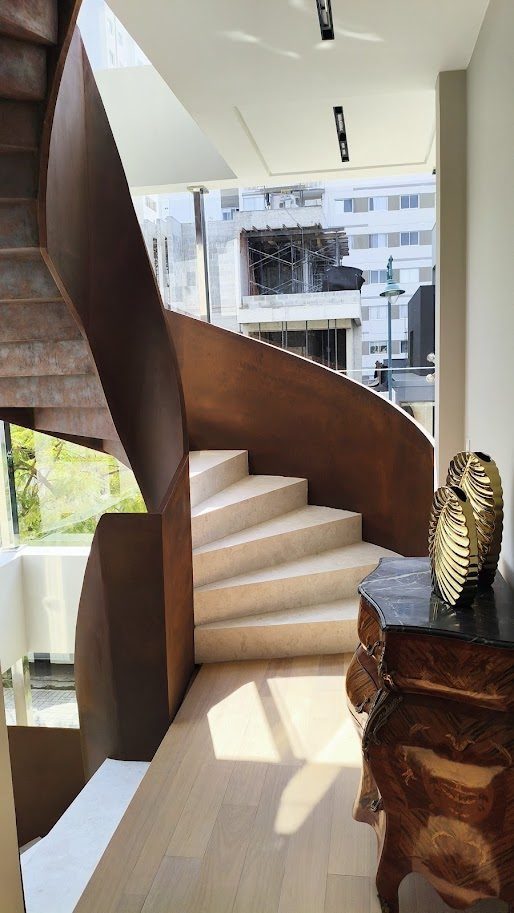 Escada helicoidal em aço corten com degraus de pedra clara