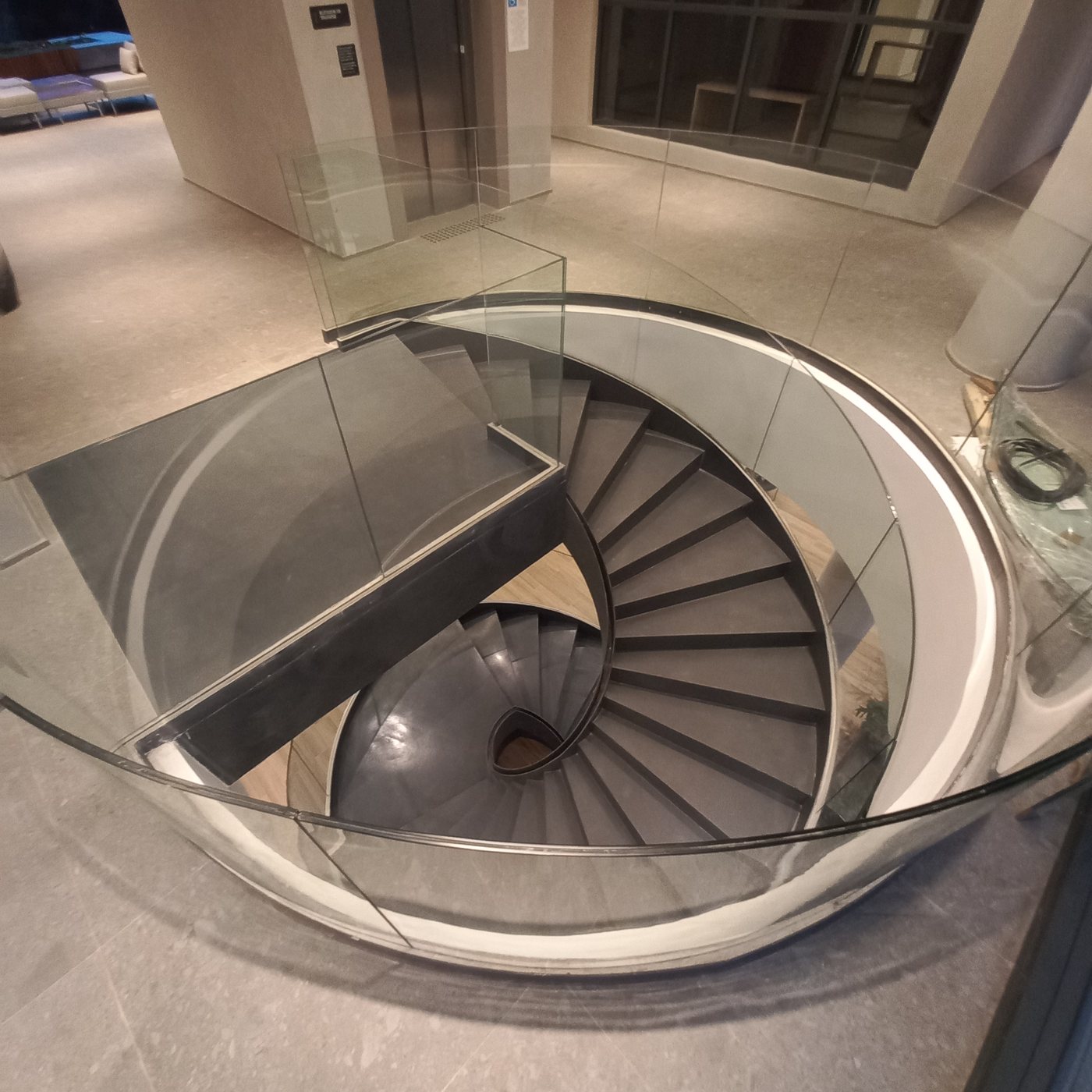 Escada helicoidal com guarda-corpo de vidro curvo vista do alto em um hall